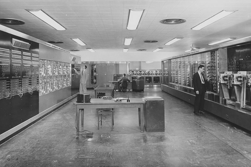Over the years, the Mark I (pictured at right) remained in good company in the basement of the Cruft Laboratory. The UNIVAC I (center) was a machine Grace Hopper helped to develop after she left Harvard in 1949; she also invented the first compiler. This picture was taken in 1956, the year the Sperry Rand Corporation donated the machine to the University. --Courtesy of the Harvard University Archives (HUGFP 59.10).
