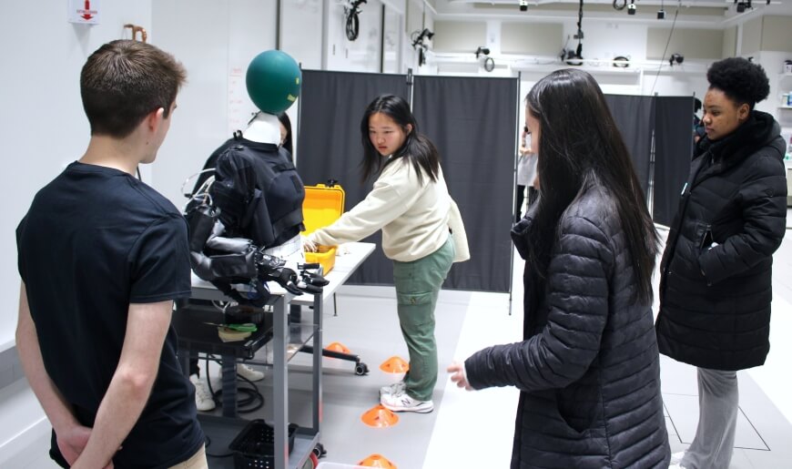 High school students manipulate a Harvard Biodesign Lab upper-extremity exosuit at Biomechanics Outreach Day at the Science and Engineering Complex