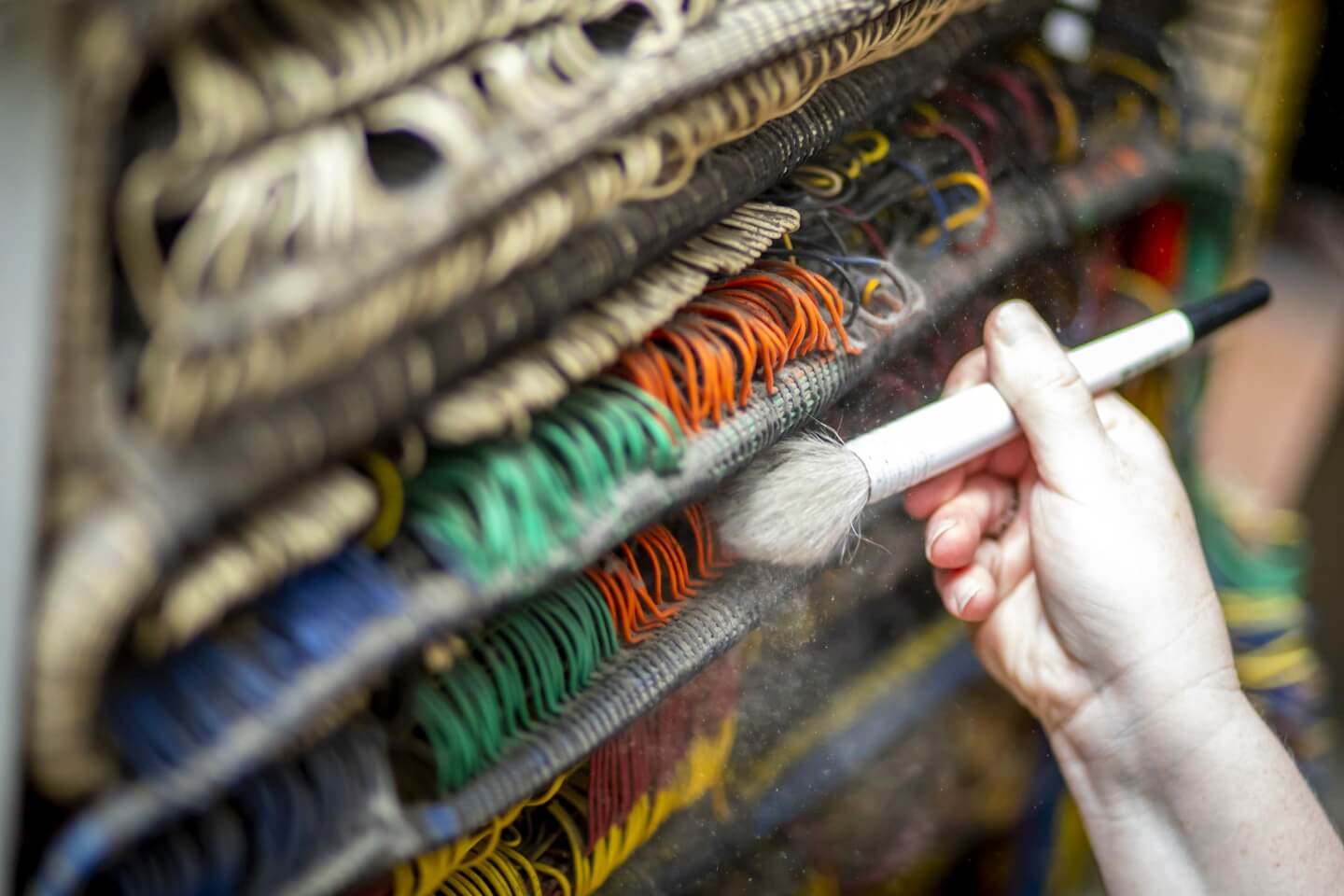 A brush runs along hundreds of wires in blue, orange, green, and beige varieties.