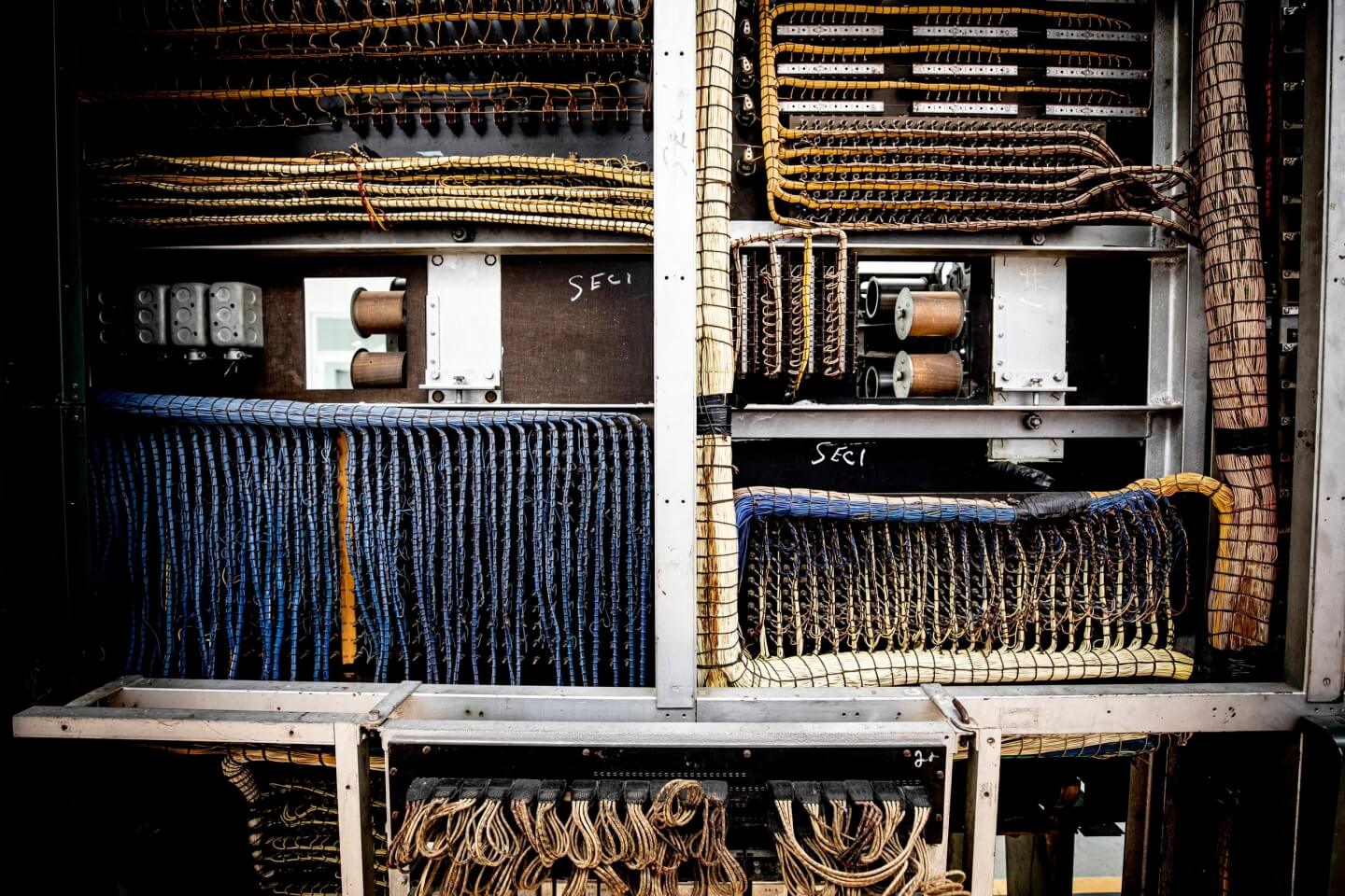 Blue and yellow cords and cables squeeze tighly inside grid-like partitions of the calculator.