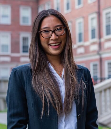 Photo of Michelle Doan, A.B. ‘25, in front of a red brick Harvard building