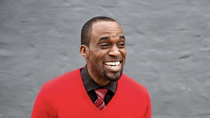 Harvard SEAS alum Victor Udoewa wearing a red sweater, black shirt and red striped tie