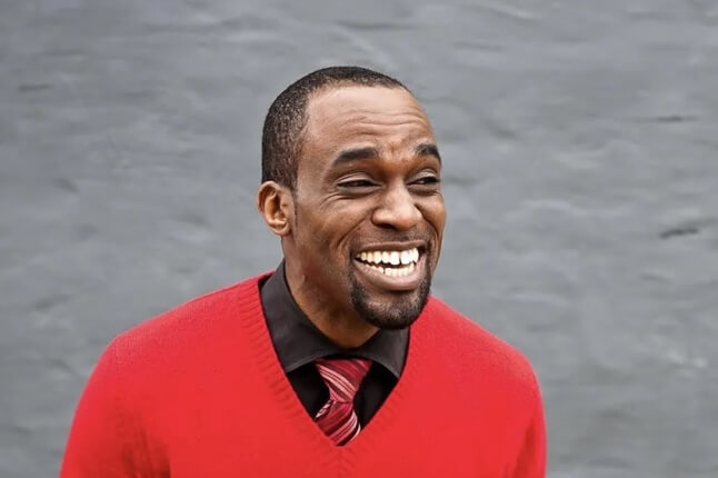 Harvard SEAS alum Victor Udoewa wearing a red sweater, black shirt and red striped tie